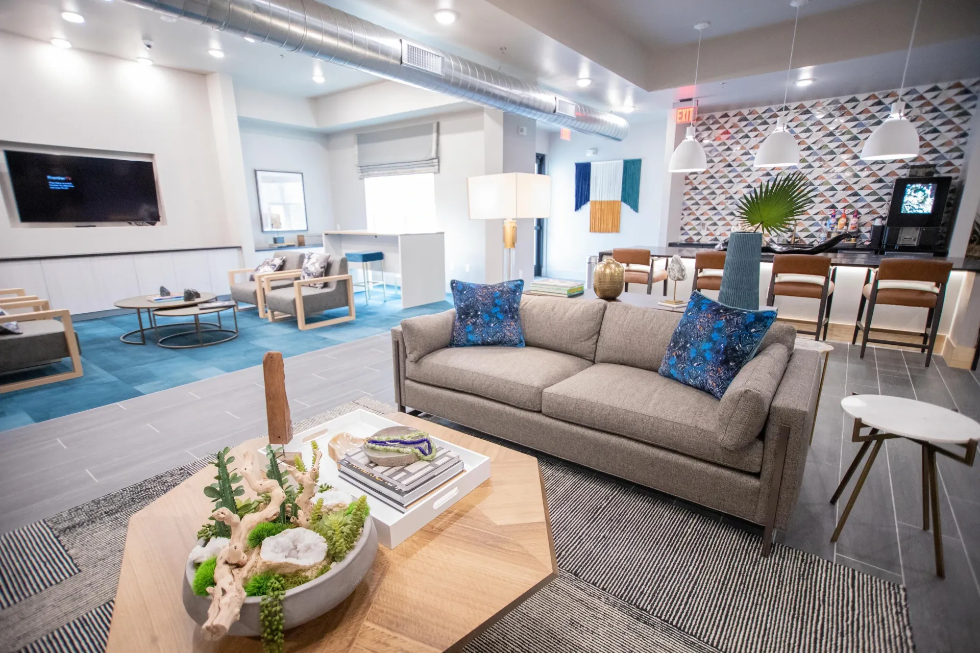Contemporary residential community lounge with sofa, coffee table, and bar seating.