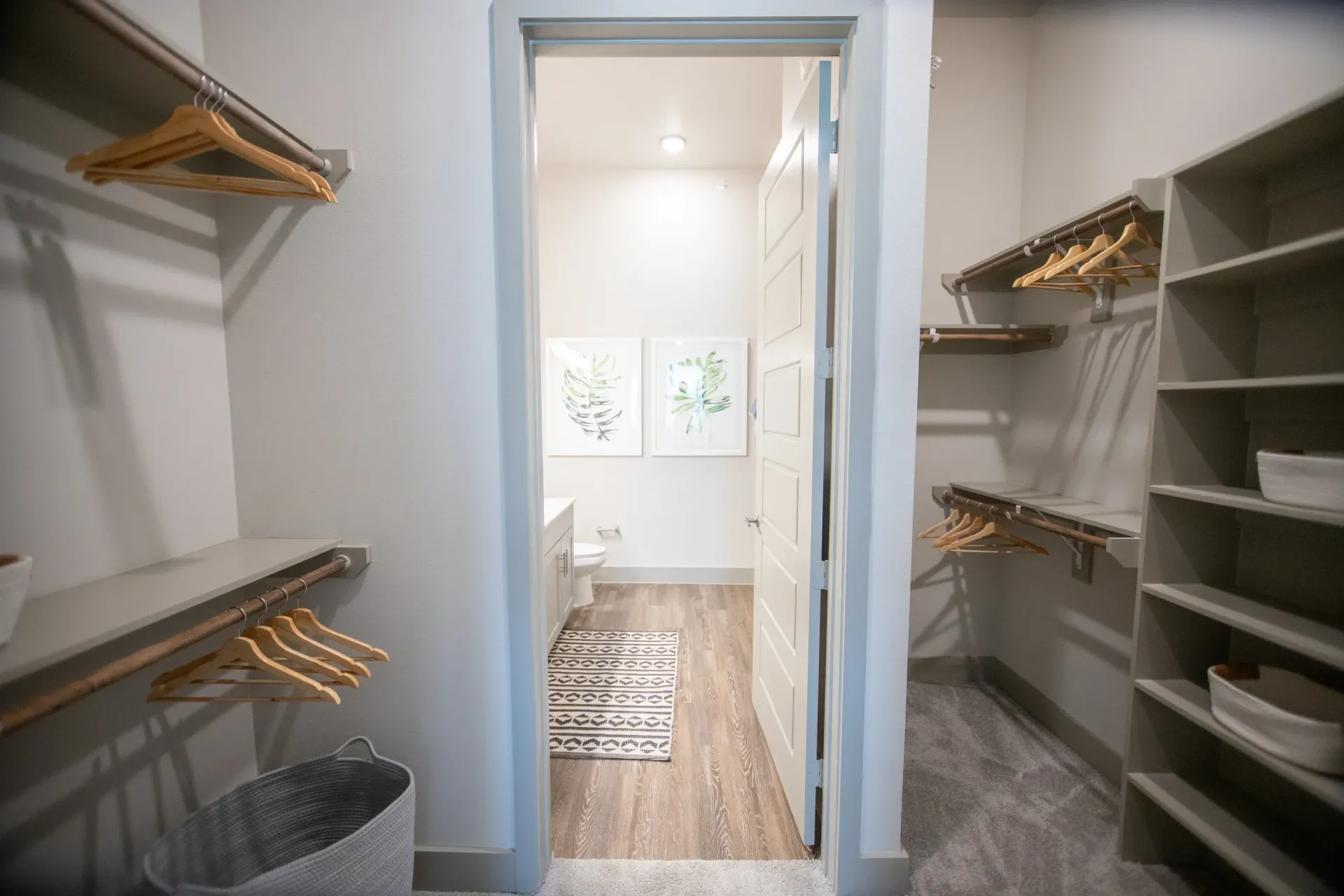 Walk-in closet with shelves and hanging rods, opening to a bathroom.