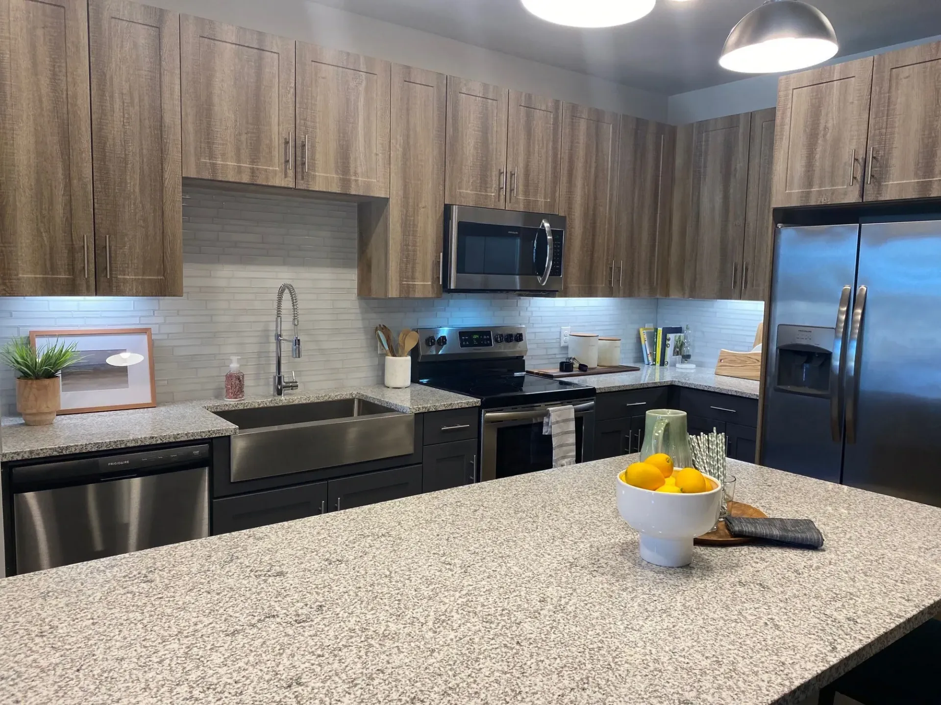 Modern apartment kitchen with granite countertops, stainless steel appliances, and an island.