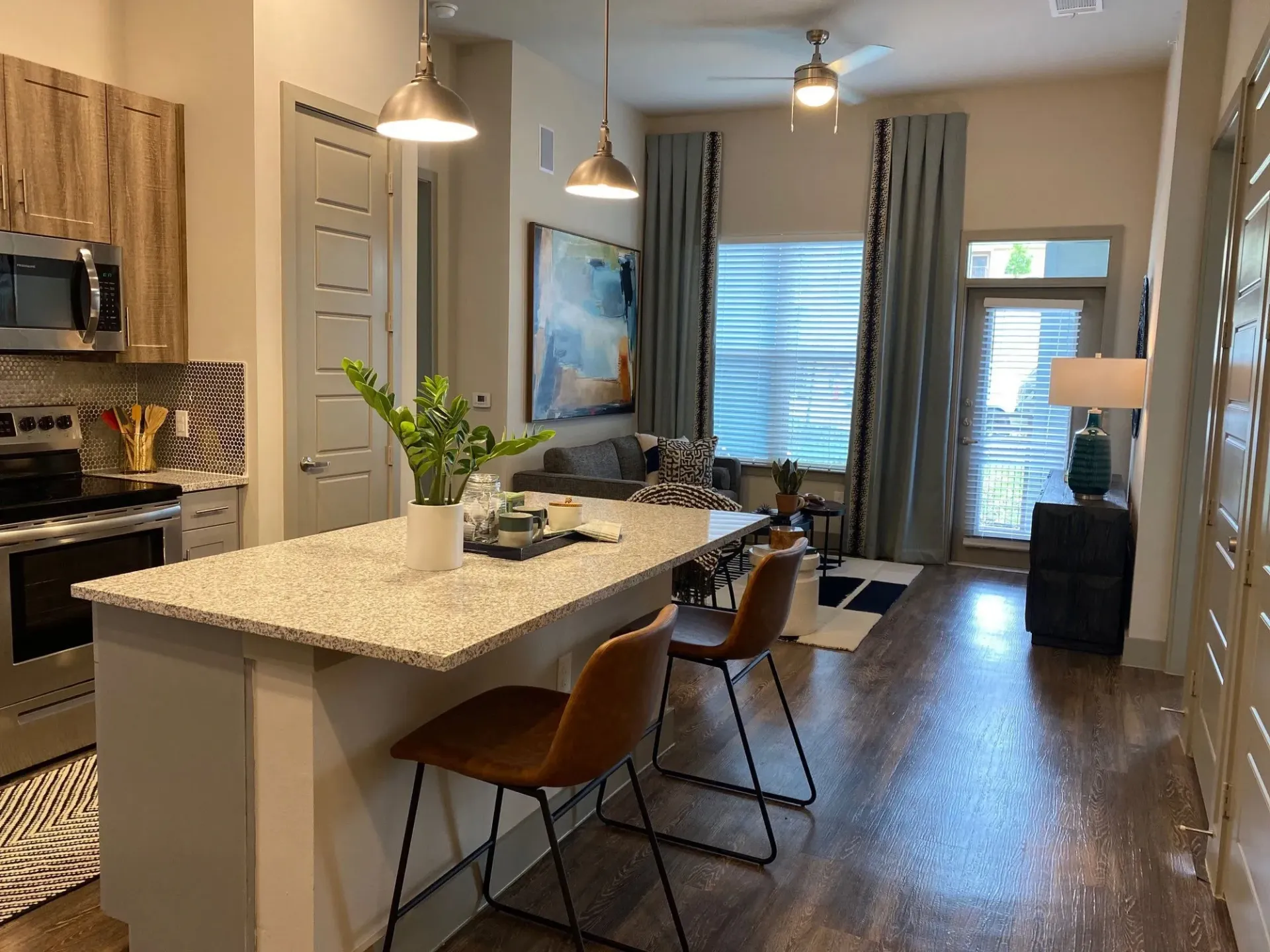 Open-concept kitchen and living area with granite island and seating, stainless appliances.