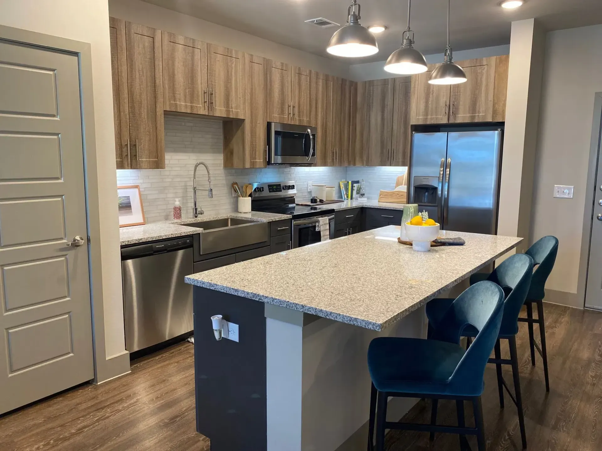 Modern apartment kitchen with an island, granite countertops, and stainless steel appliances.