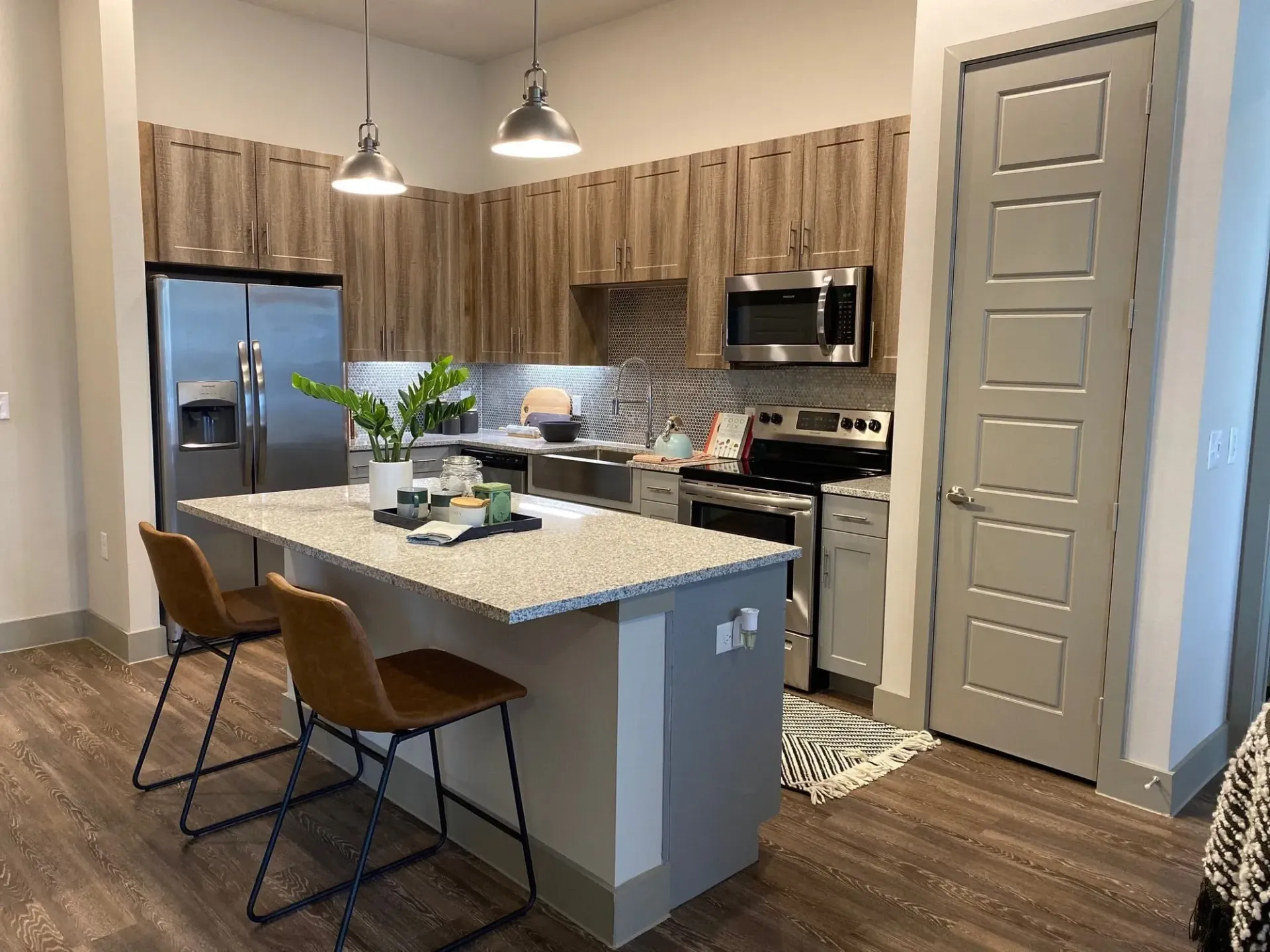 Modern apartment kitchen with an island, granite countertops, and stainless-steel appliances.
