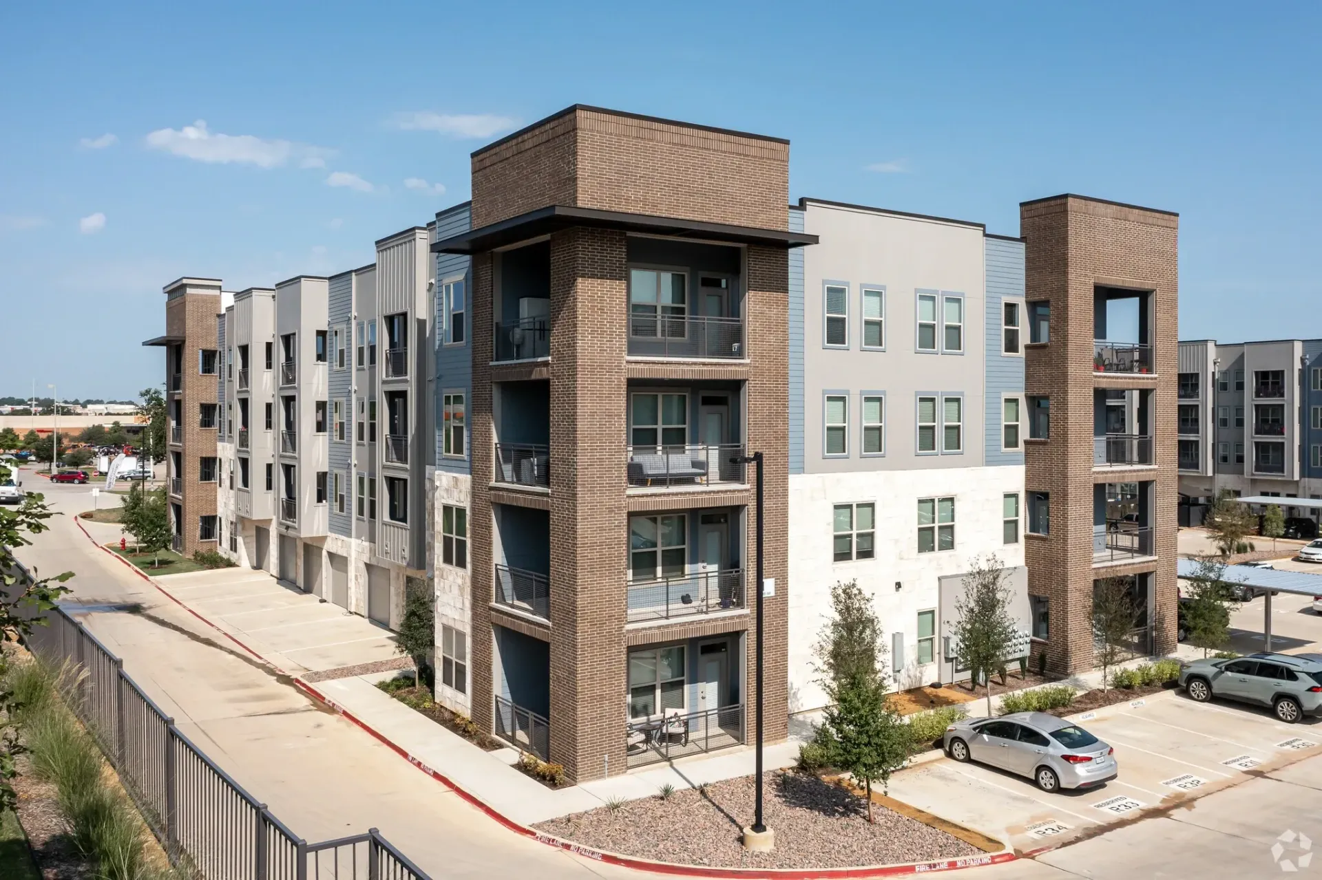 Exterior view of a modern apartment building with balconies and parking.