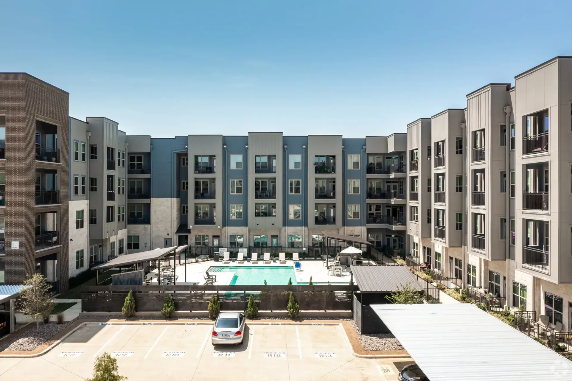 Exterior view of a modern apartment complex courtyard with a central pool.