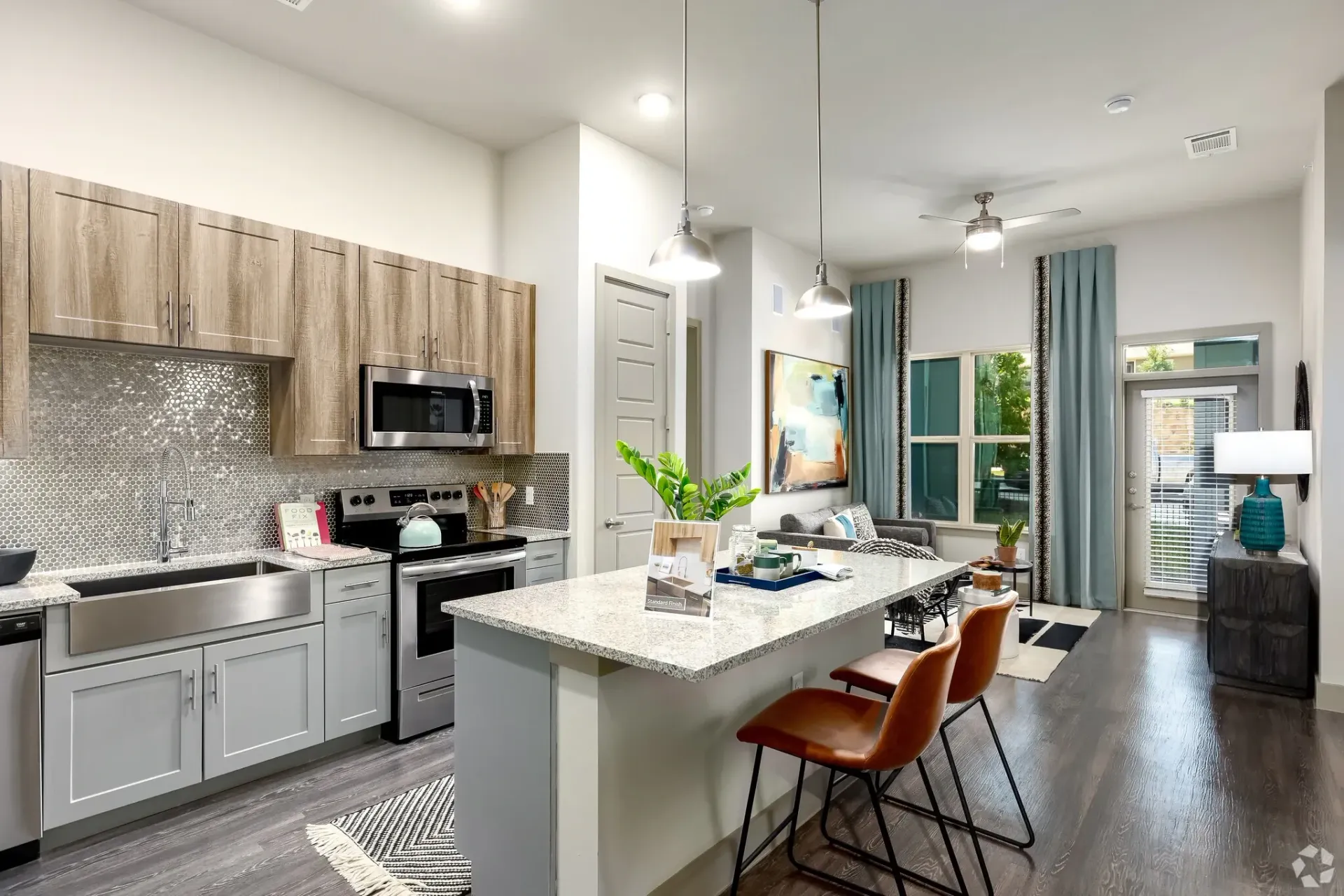 Open-concept kitchen with granite island, stainless appliances, gray cabinets, and pendant lighting.
