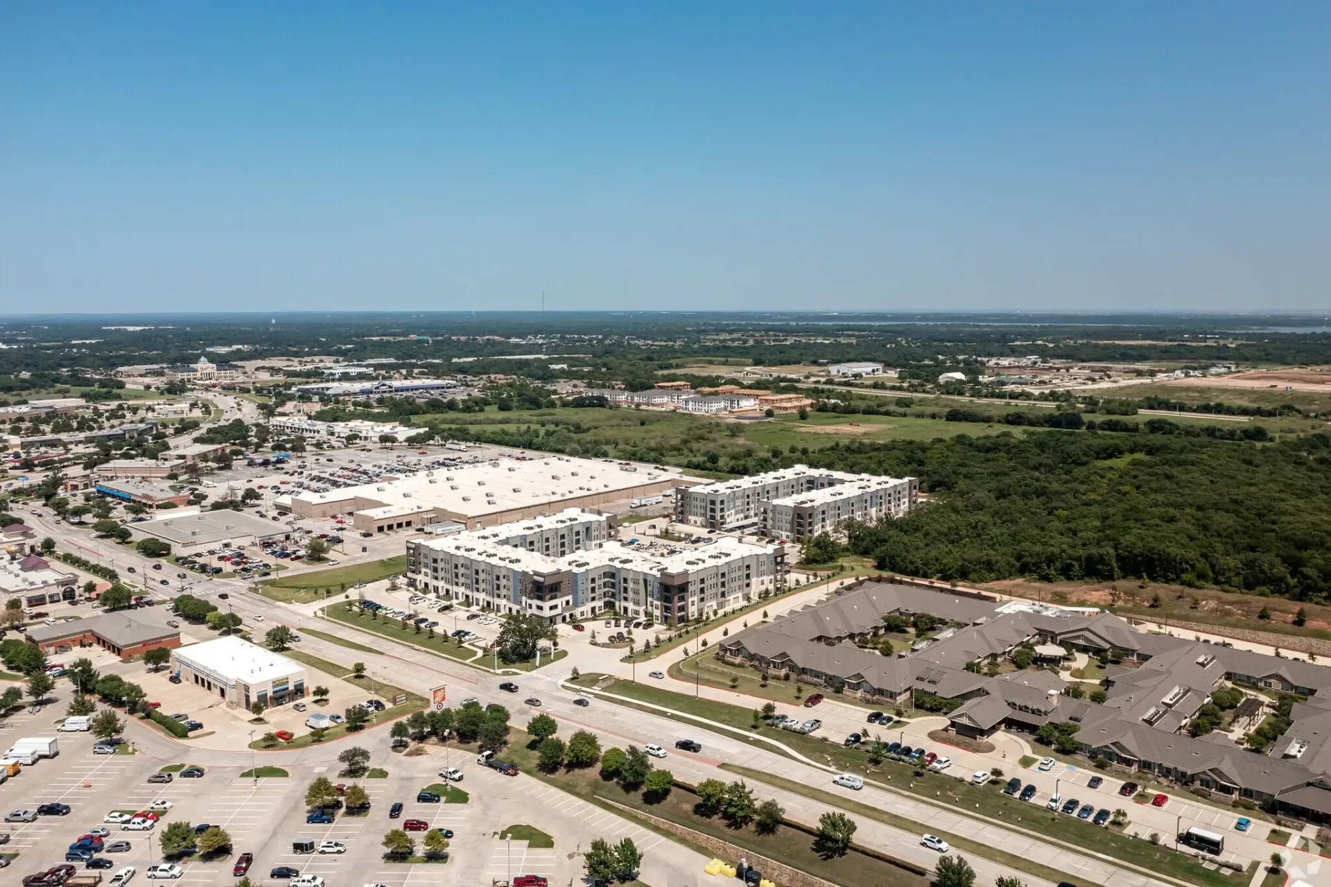 Aerial view of a large apartment complex with multiple buildings, parking lots, and surrounding green space.