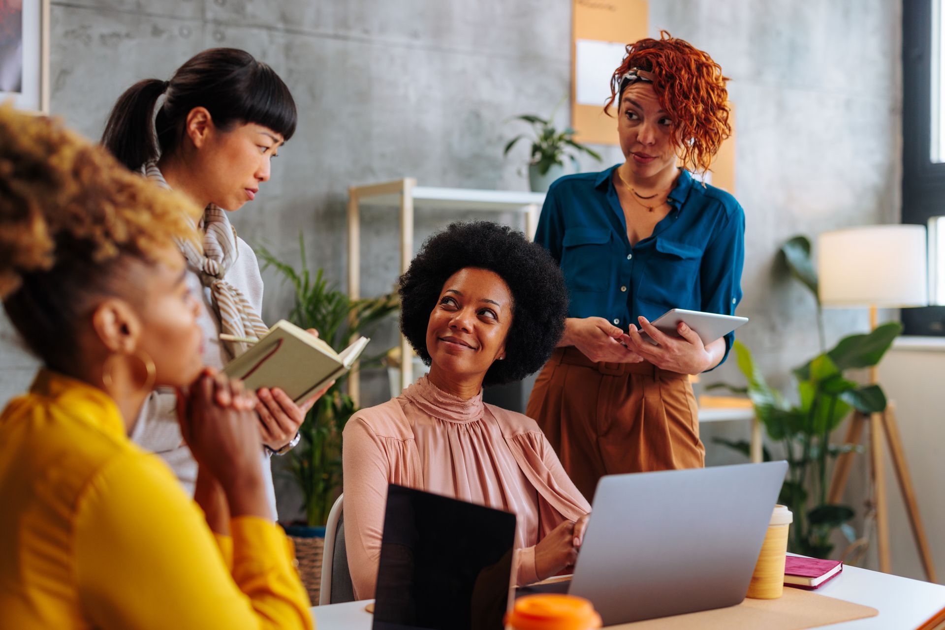 Coworkers discussing ideas around a laptop in a bright office