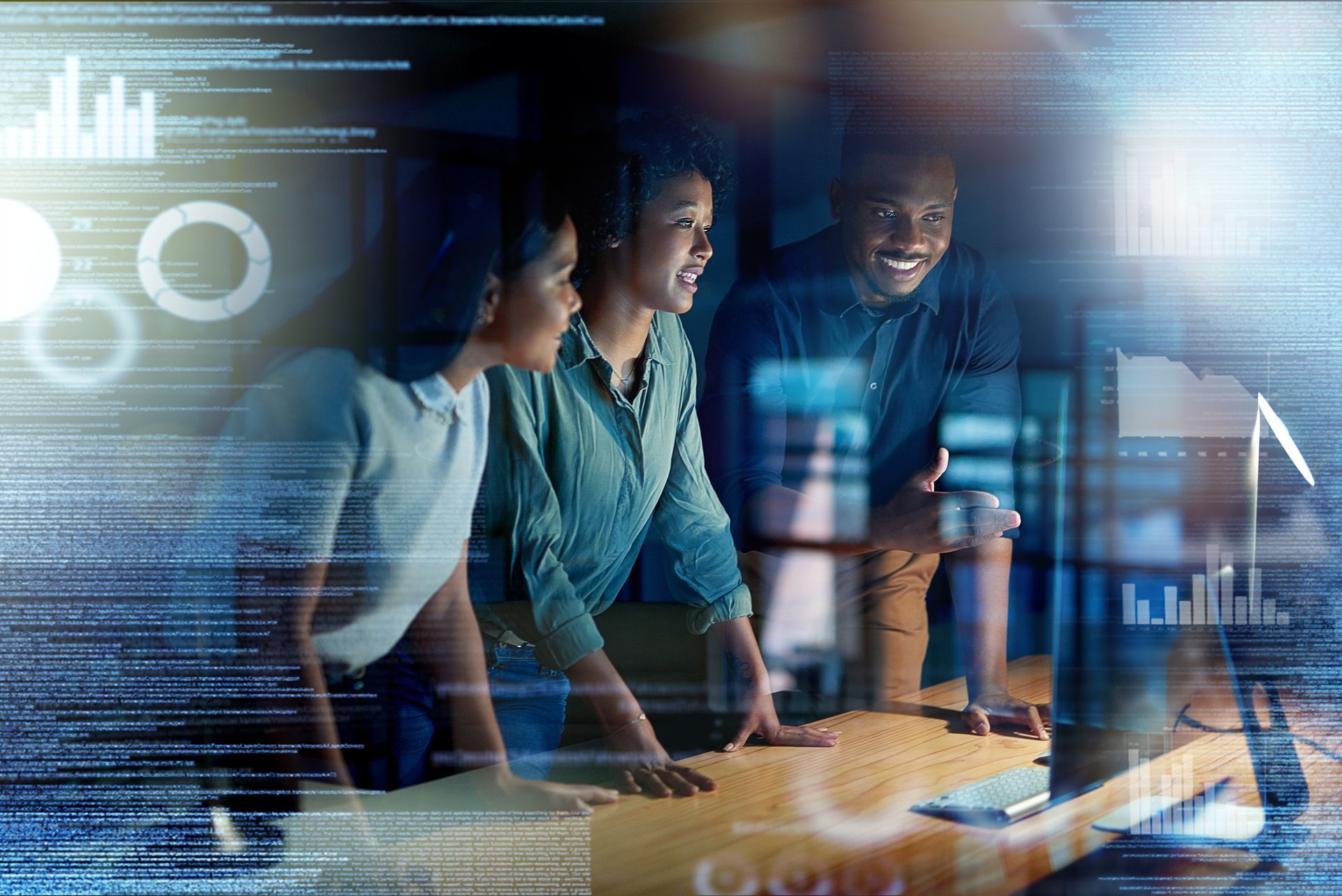 Three coworkers review data on a glowing computer screen in a modern office.