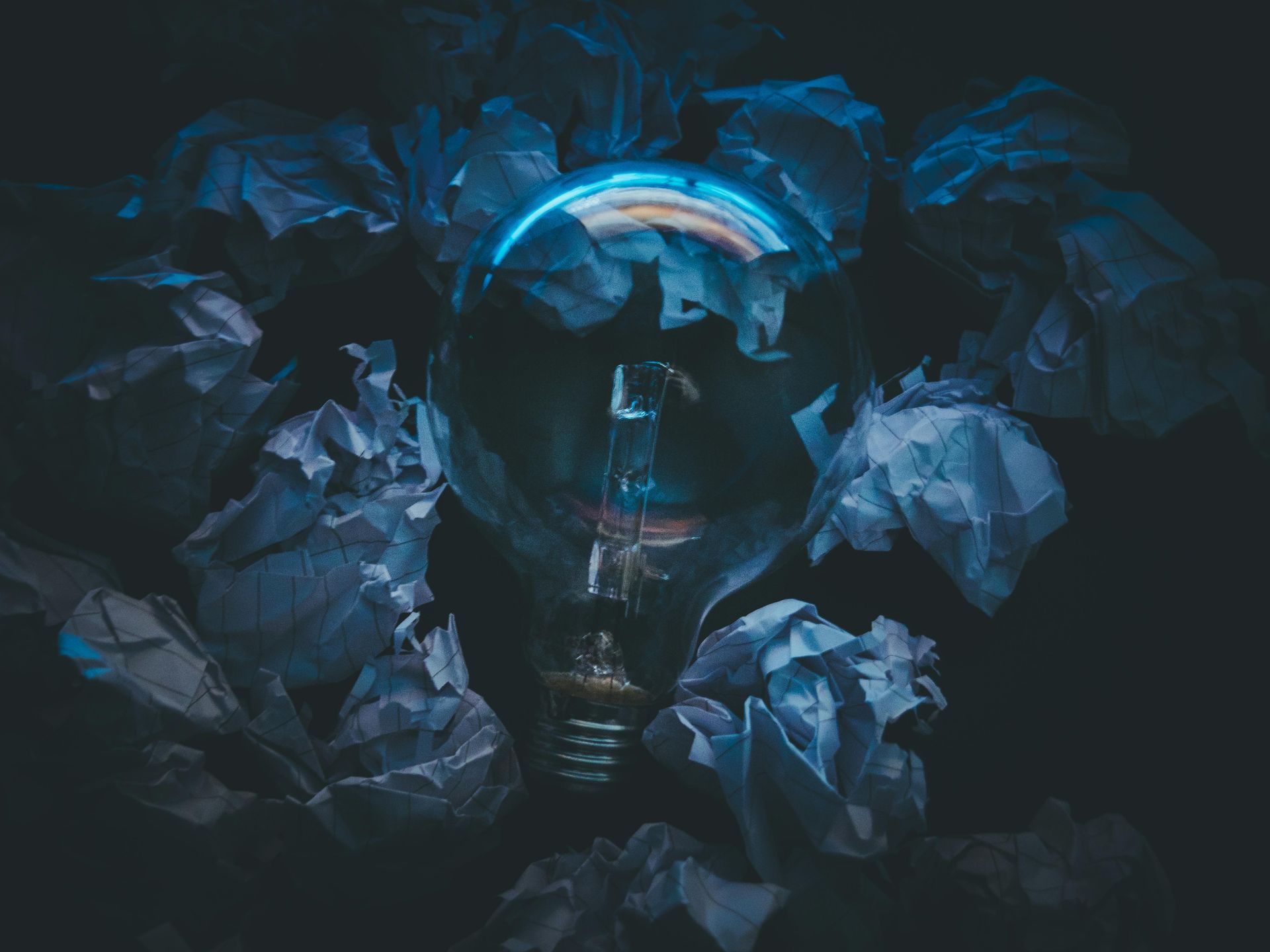 Blue-toned abstract floral arrangement with dark background and a glowing crescent light at the center