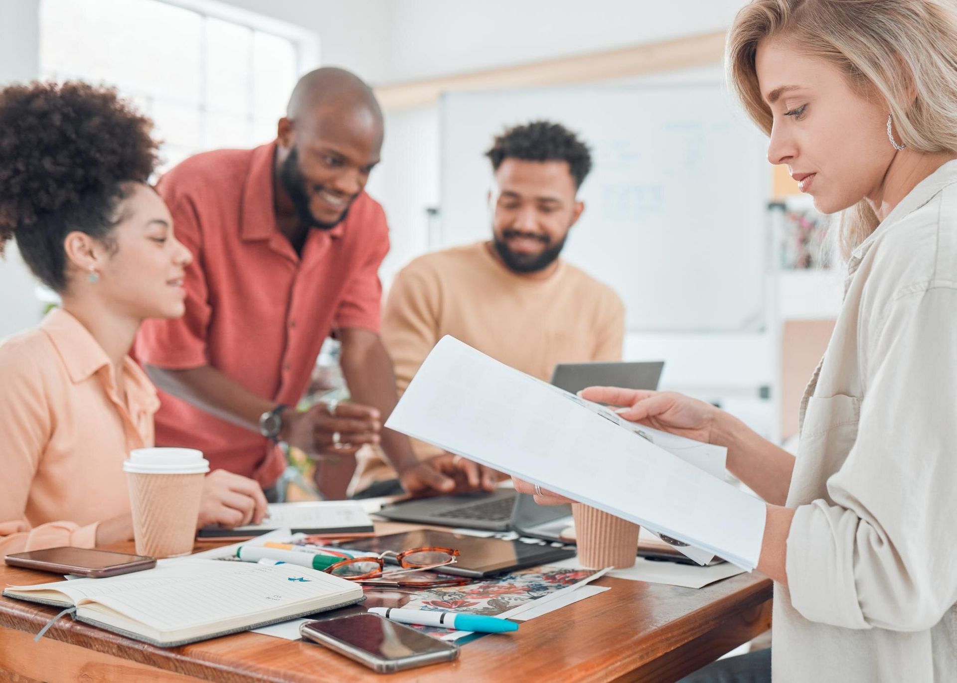 People collaborating around a table, reviewing papers and supplies in a bright office meeting room