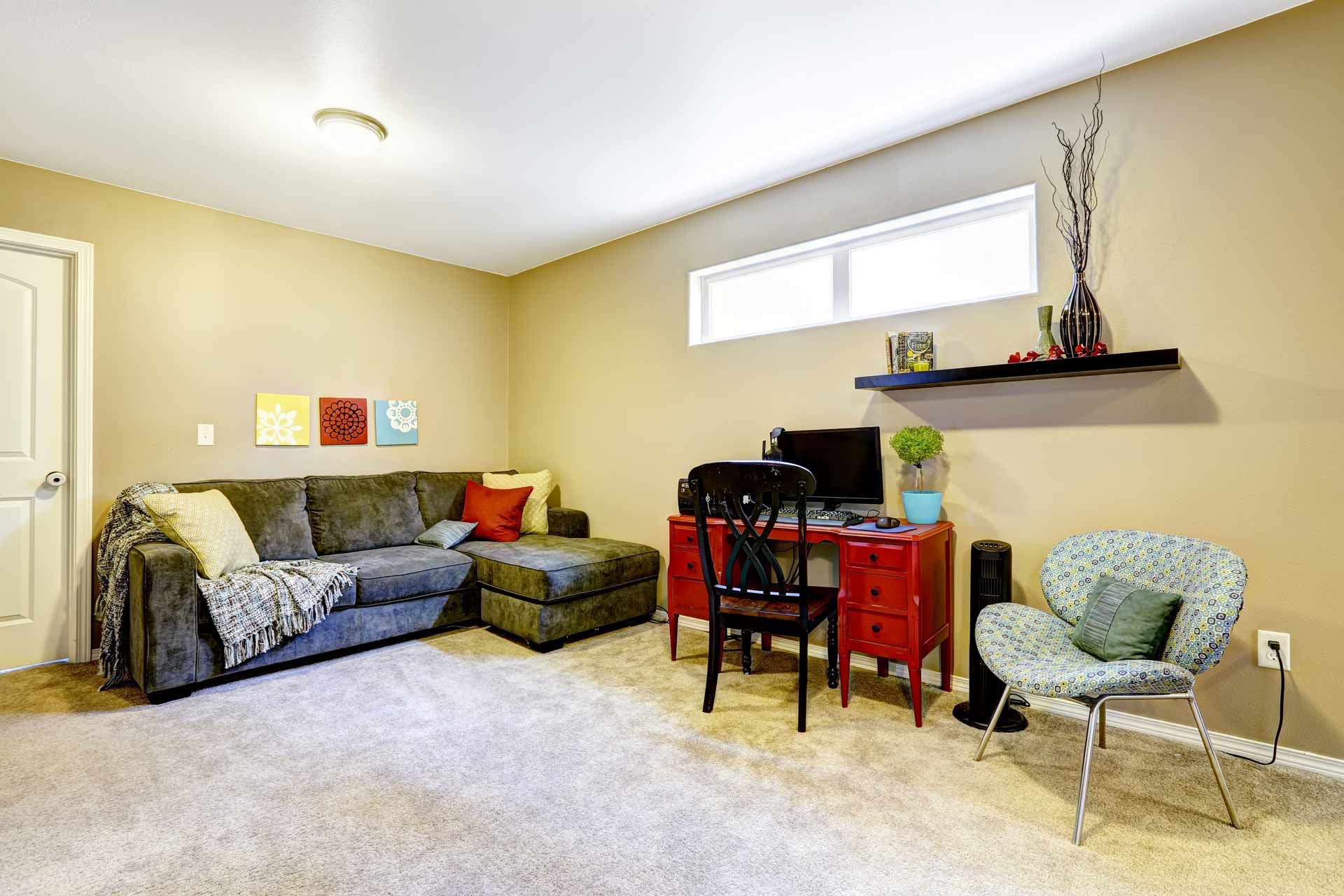 Cozy living room with a sectional sofa, desk, and accent chair against tan walls.