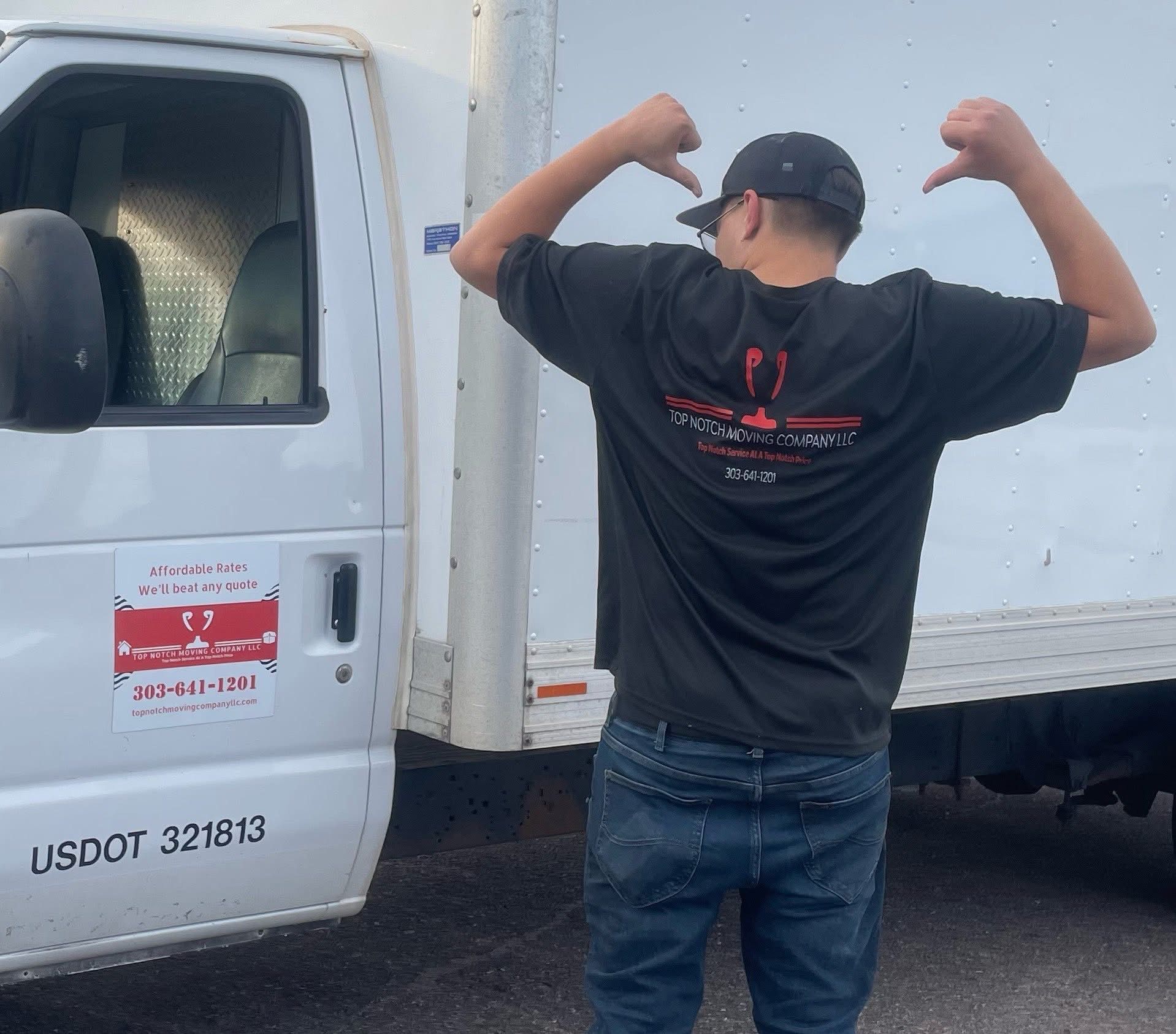 Person in a black shirt gives thumbs down, standing by a white moving truck.