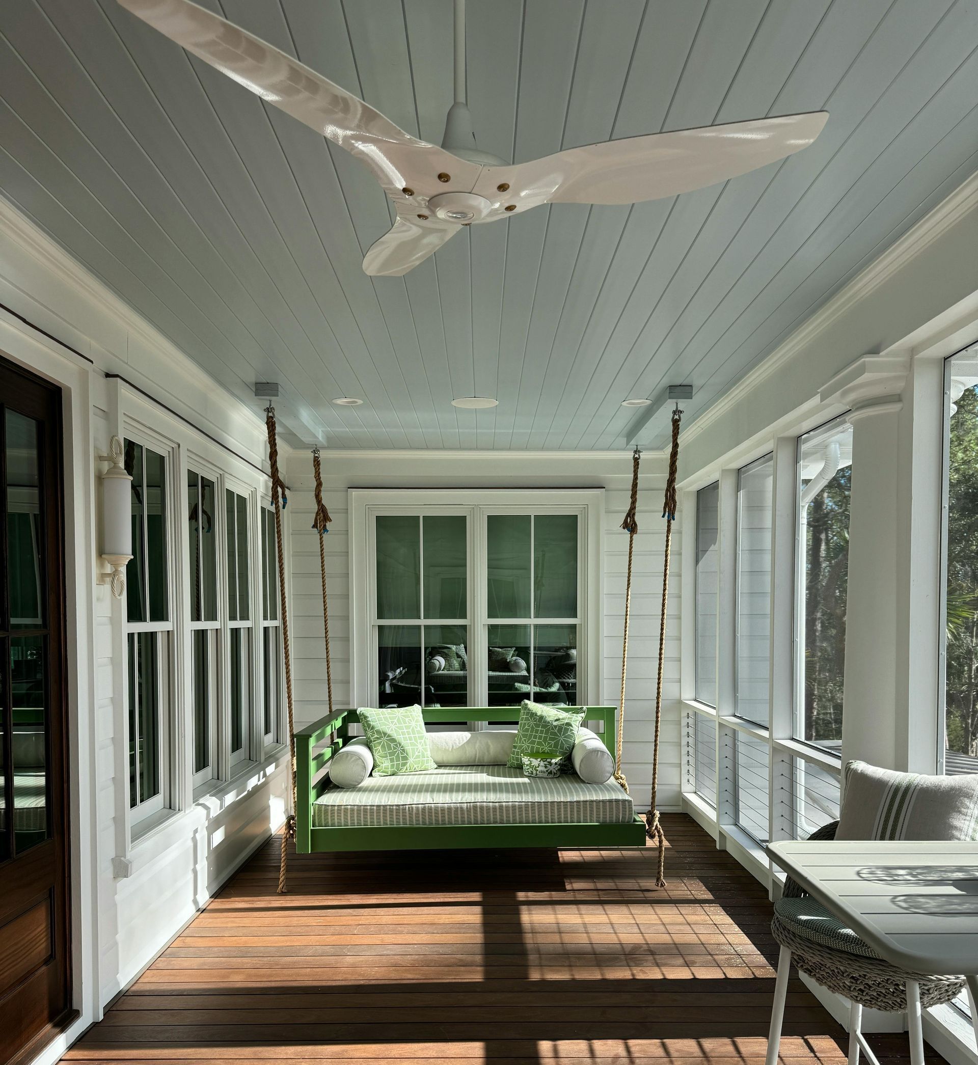 Hanging green trim daybed on expansive front porch in Virginia Beach
