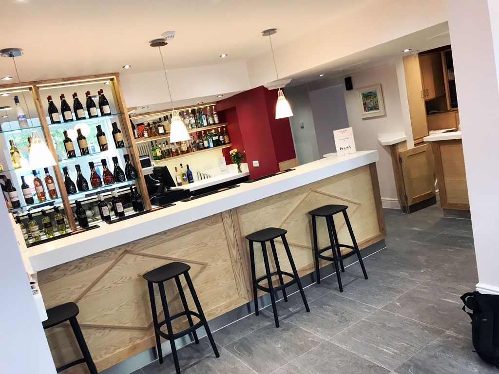 A bar with stools and bottles on the wall.