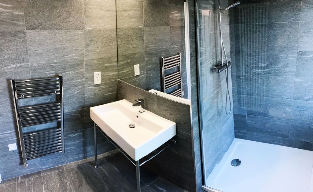 A bathroom with a sink , shower and mirror.