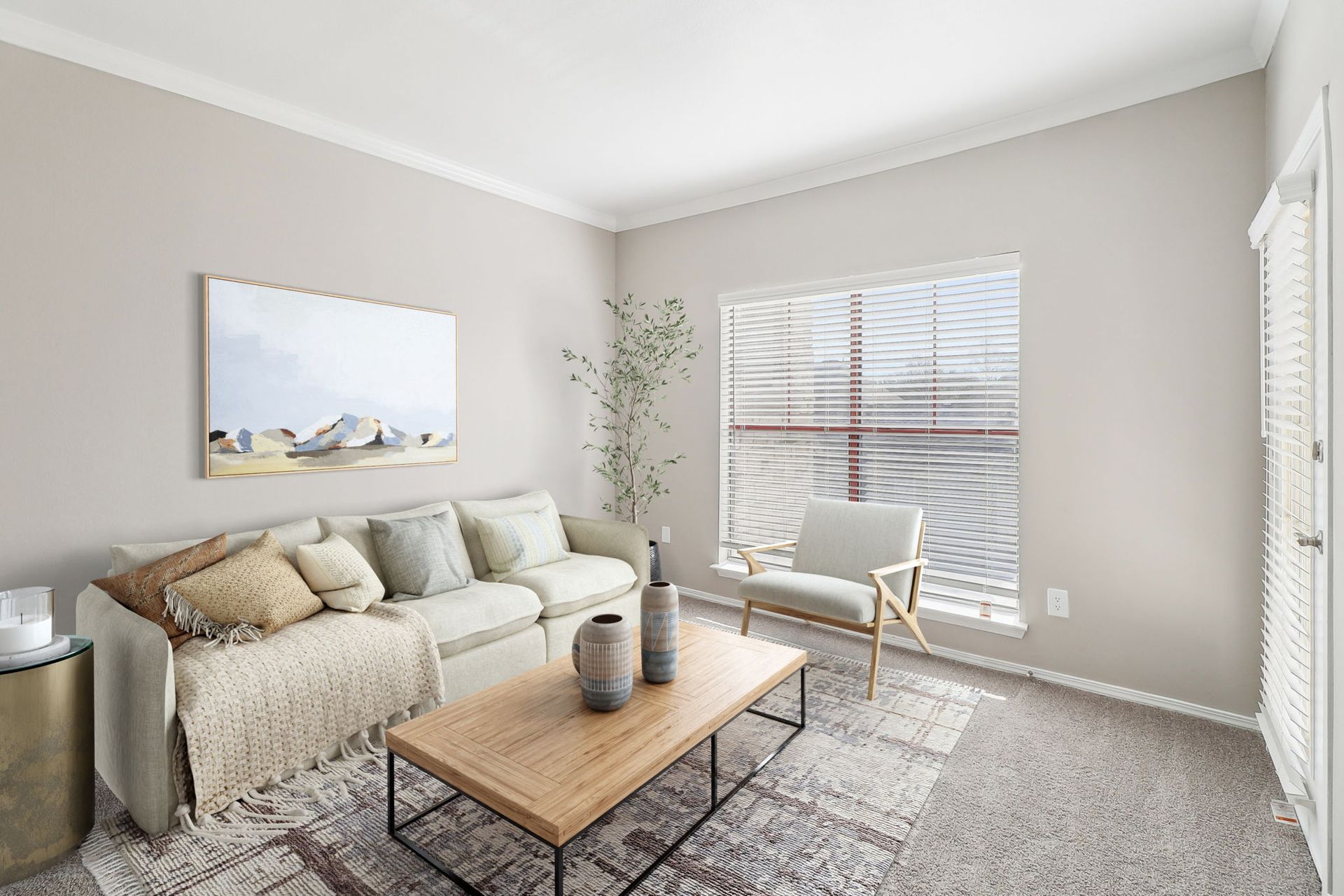 A living room with a couch , chair , coffee table and window.
