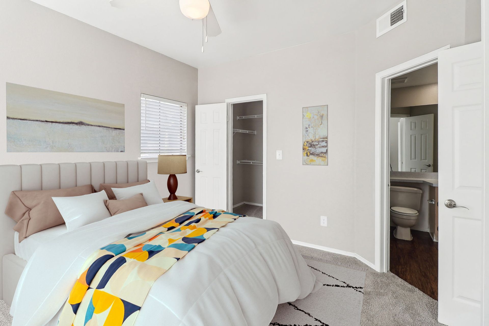 A bedroom with a large bed , a ceiling fan , and a bathroom.