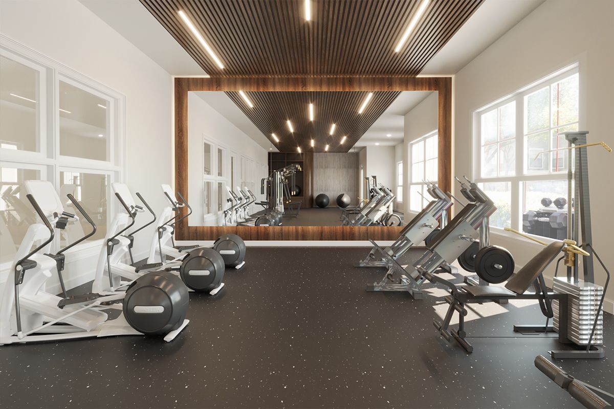 Gym interior with cardio machines, weights, and weight machines arranged in a room with large mirrors and windows.