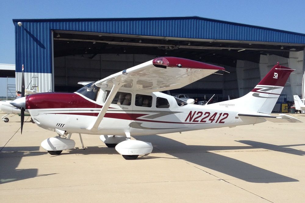 A small red and white plane with n224412 on the side is parked in front of a hangar