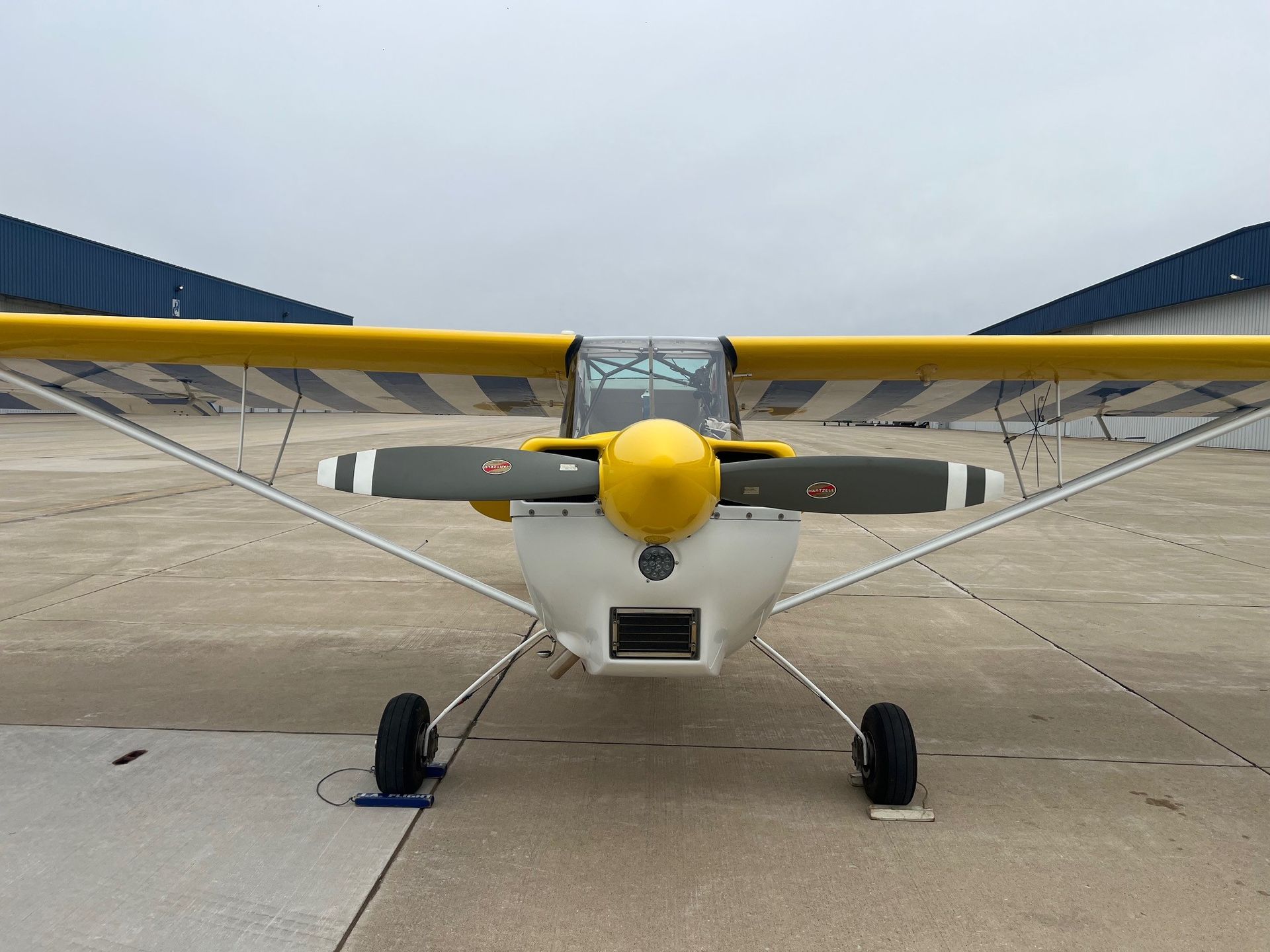 A small yellow and white plane is parked on a runway