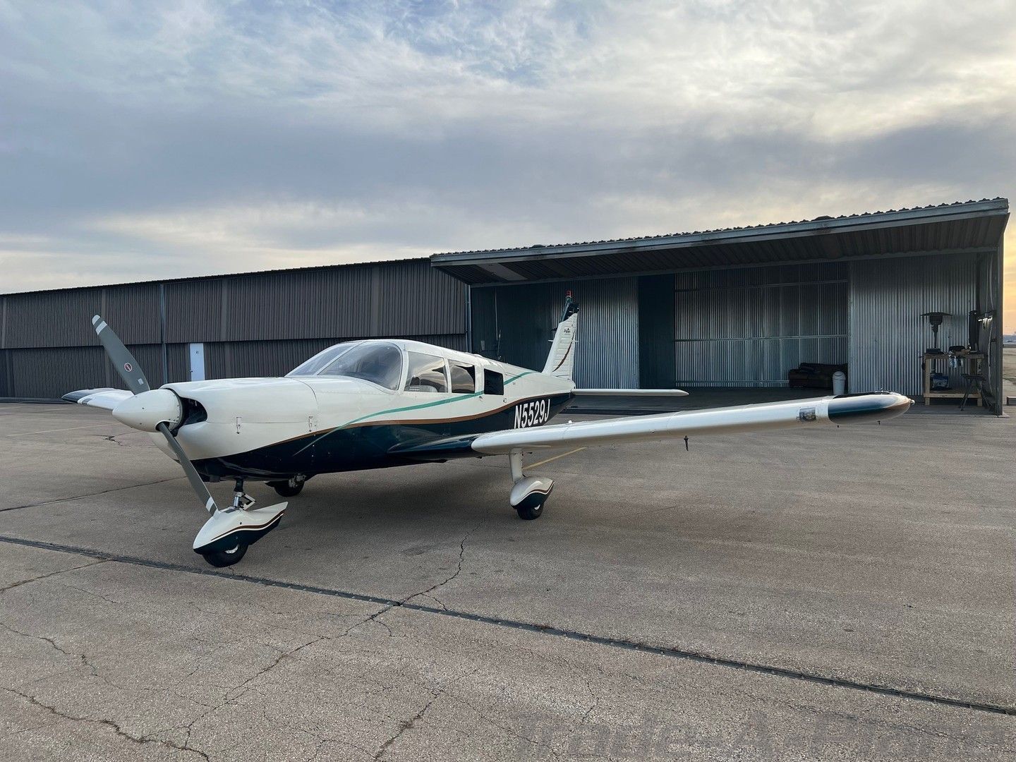 A small propeller plane is parked in front of a hangar.