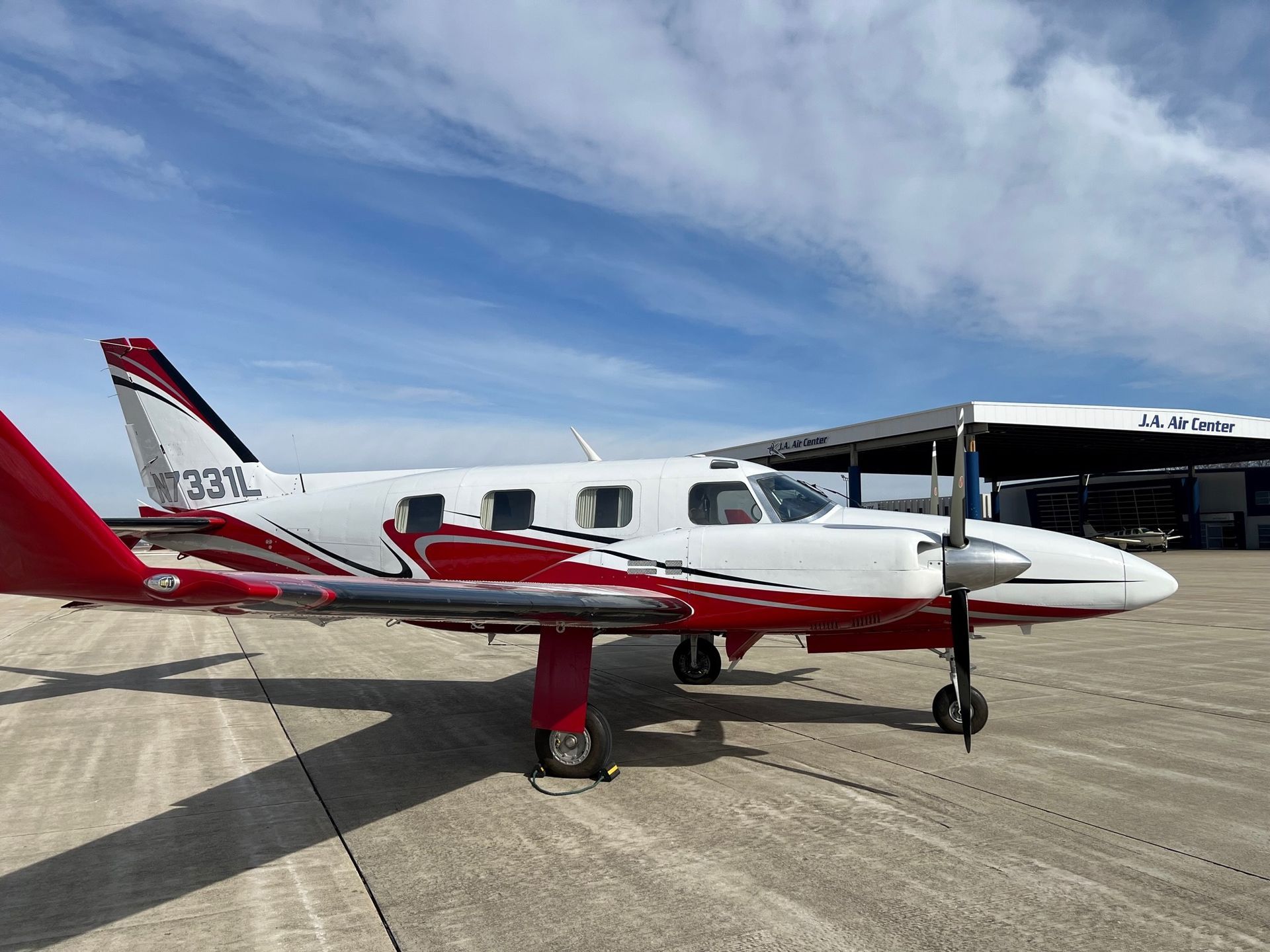 A small red and white airplane is parked on a runway.