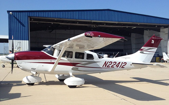 A small red and white plane with n224412 on the side is parked in front of a hangar.