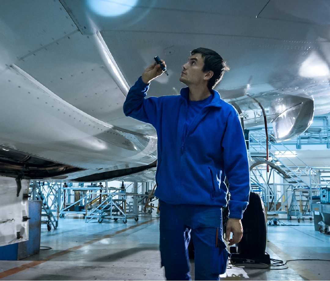 A man in a blue jacket is working on an airplane