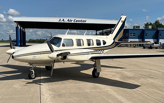 A small plane is parked in front of a building that says j.a. air center