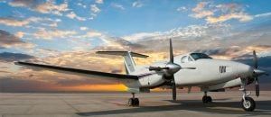A small propeller plane is parked on a runway at sunset.