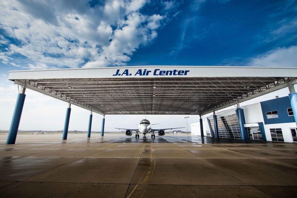 A plane is parked under a canopy at the j.a. air center