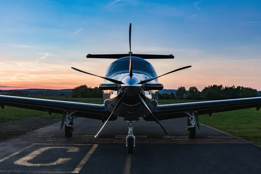A small propeller plane is parked on a runway at sunset.