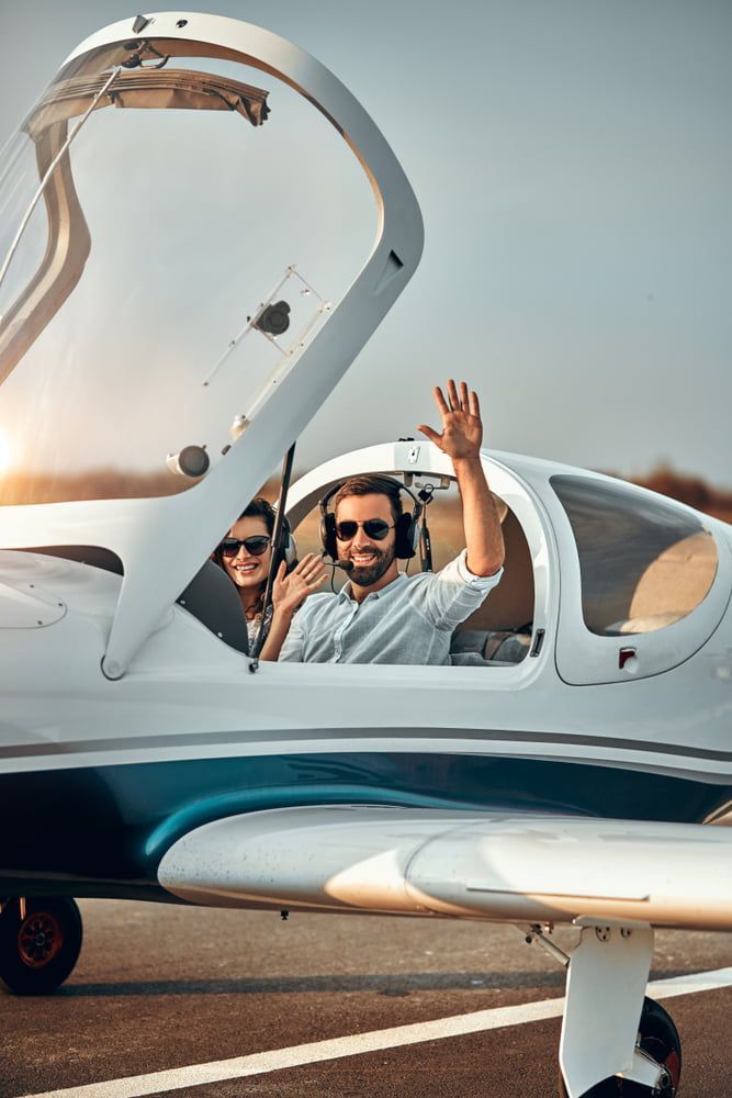 the pilot and passenger wave at the camera, they are in the cockpit testing driving planes