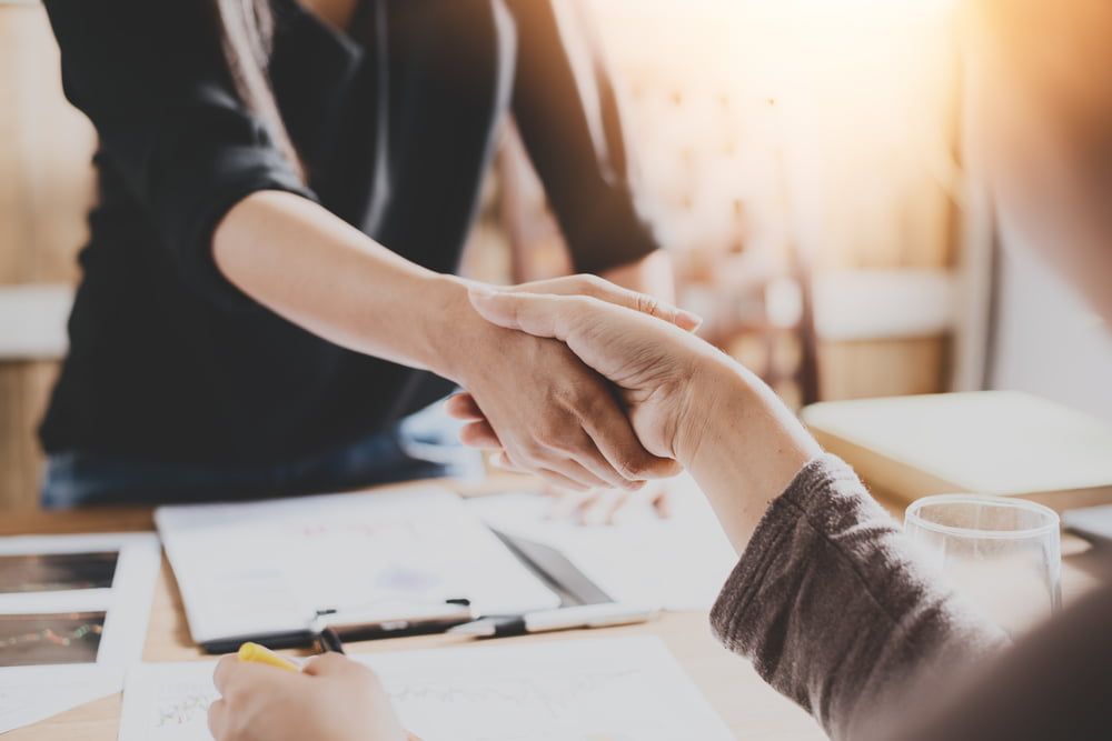 A man and a woman are shaking hands over a table.