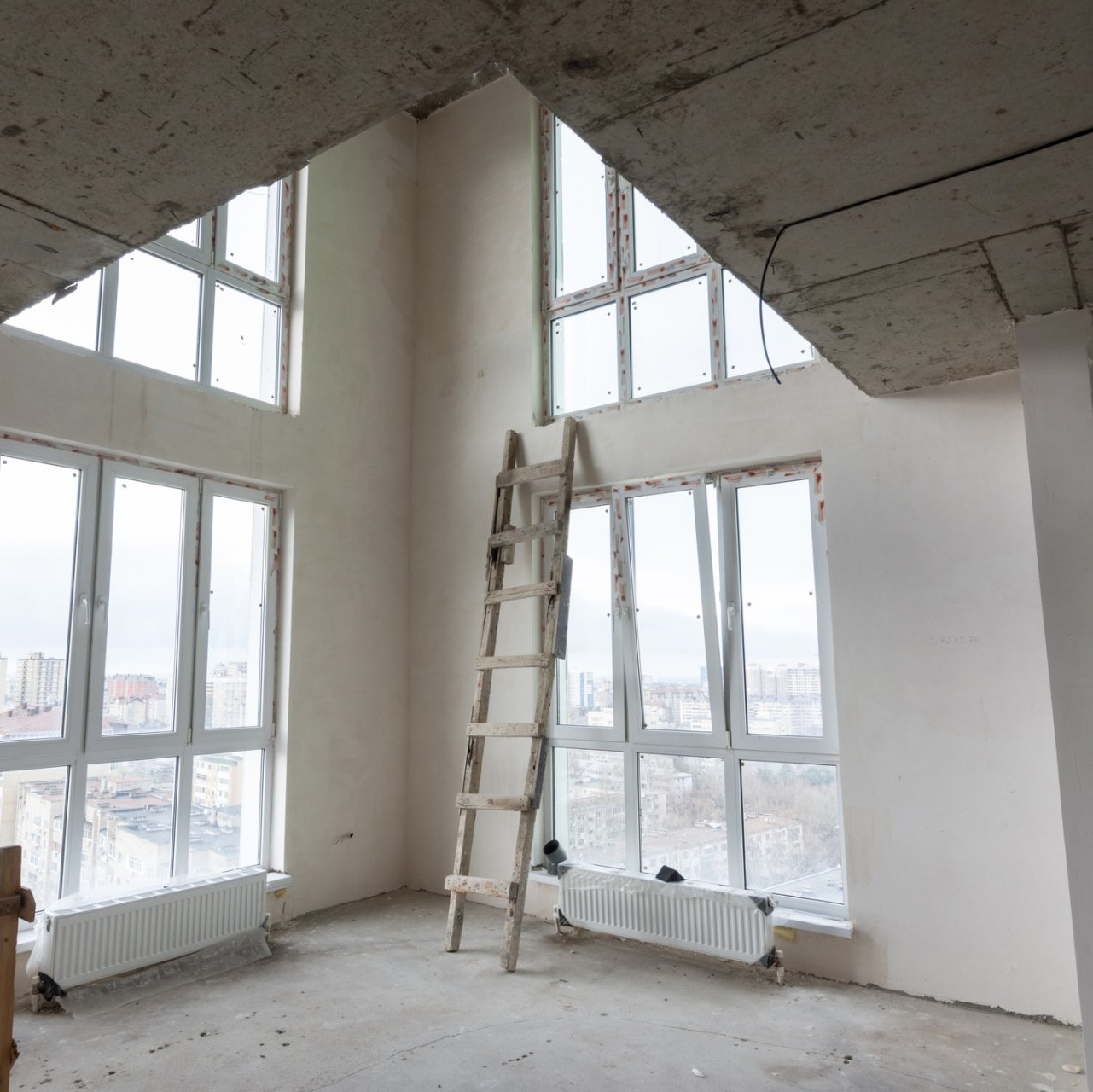 An empty room with a ladder and lots of windows