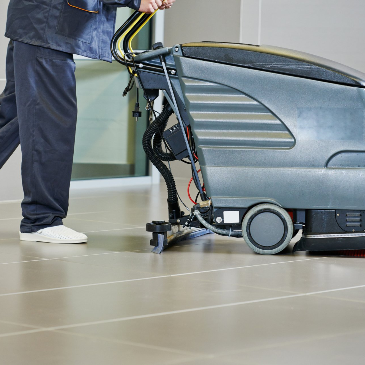 A man is using a machine to clean a tiled floor.