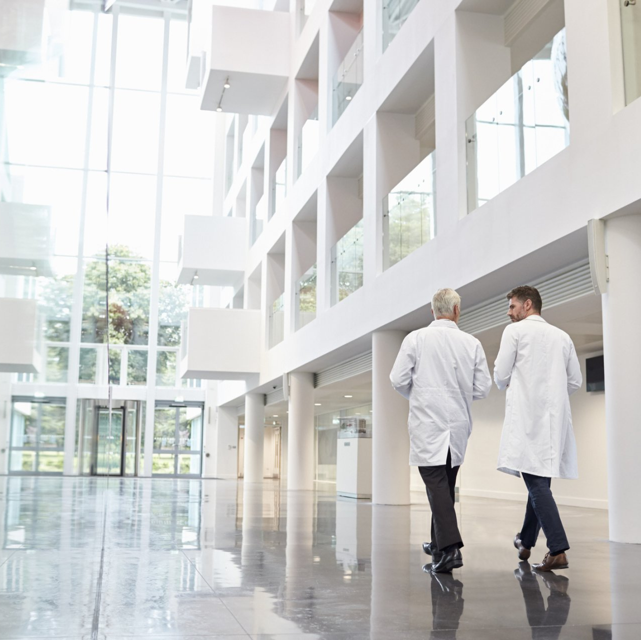 Two men in lab coats are walking down a hallway