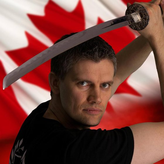A person holding a katana over their head in front of a Canadian flag.