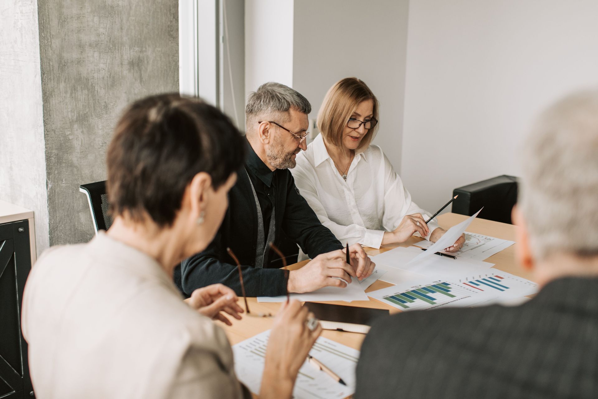 Team meeting around a conference table with papers and charts in a bright office