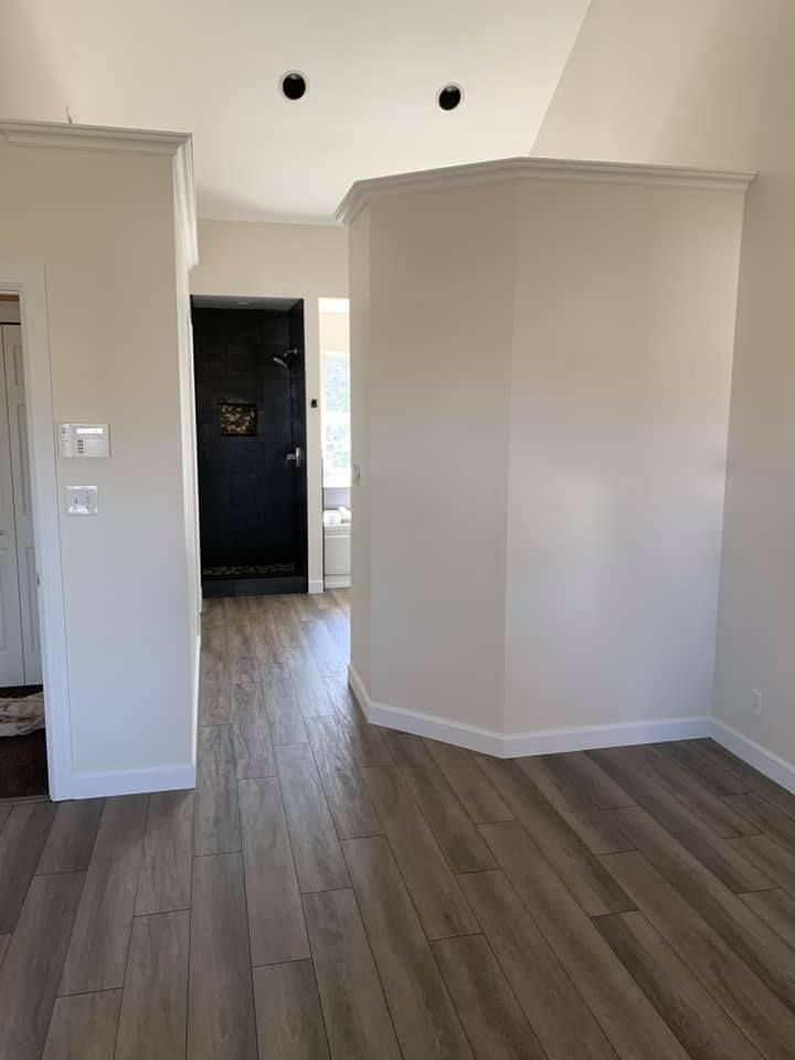 An empty room with hardwood floors and white walls.