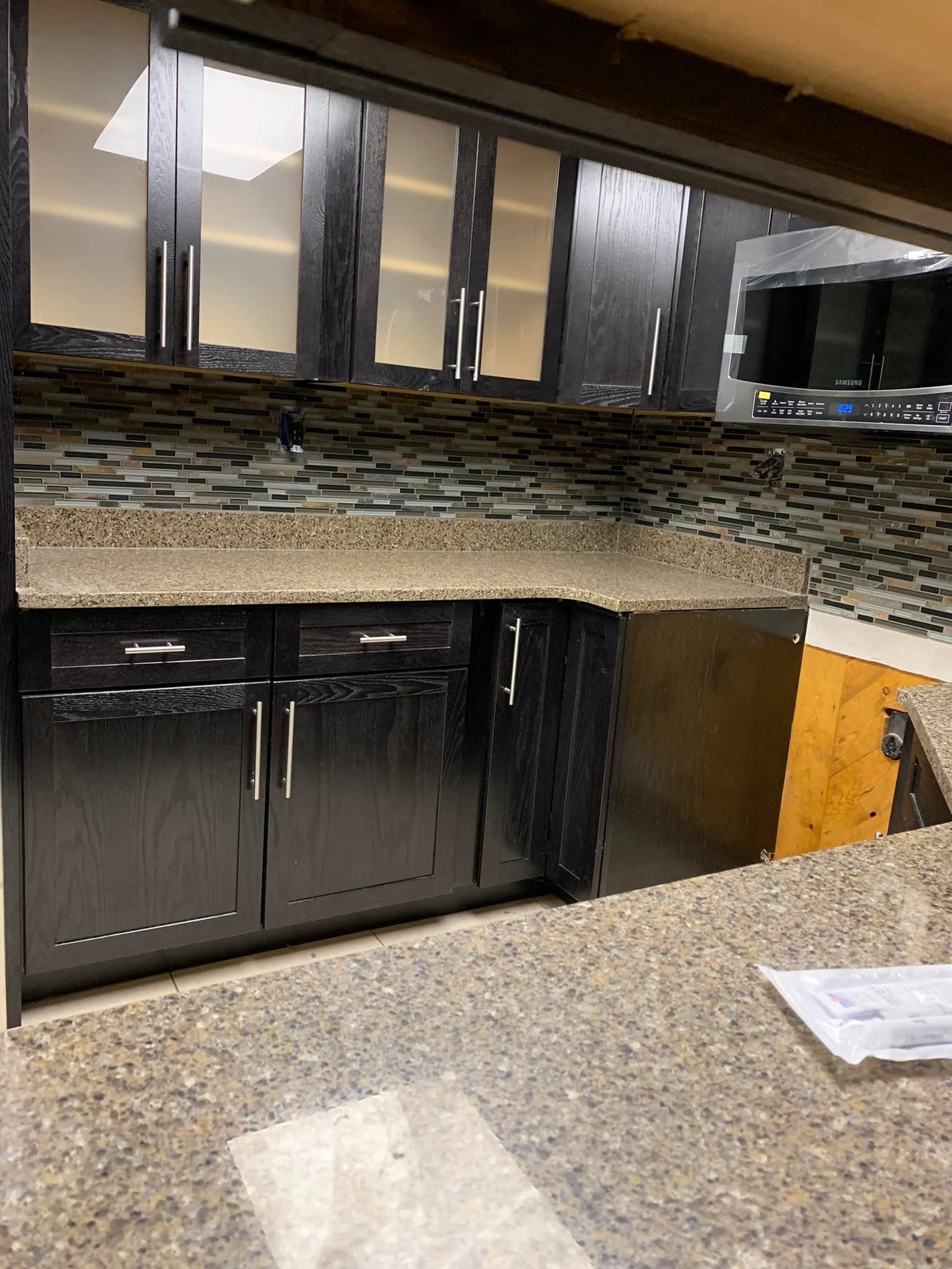 A kitchen with black cabinets and granite counter tops.