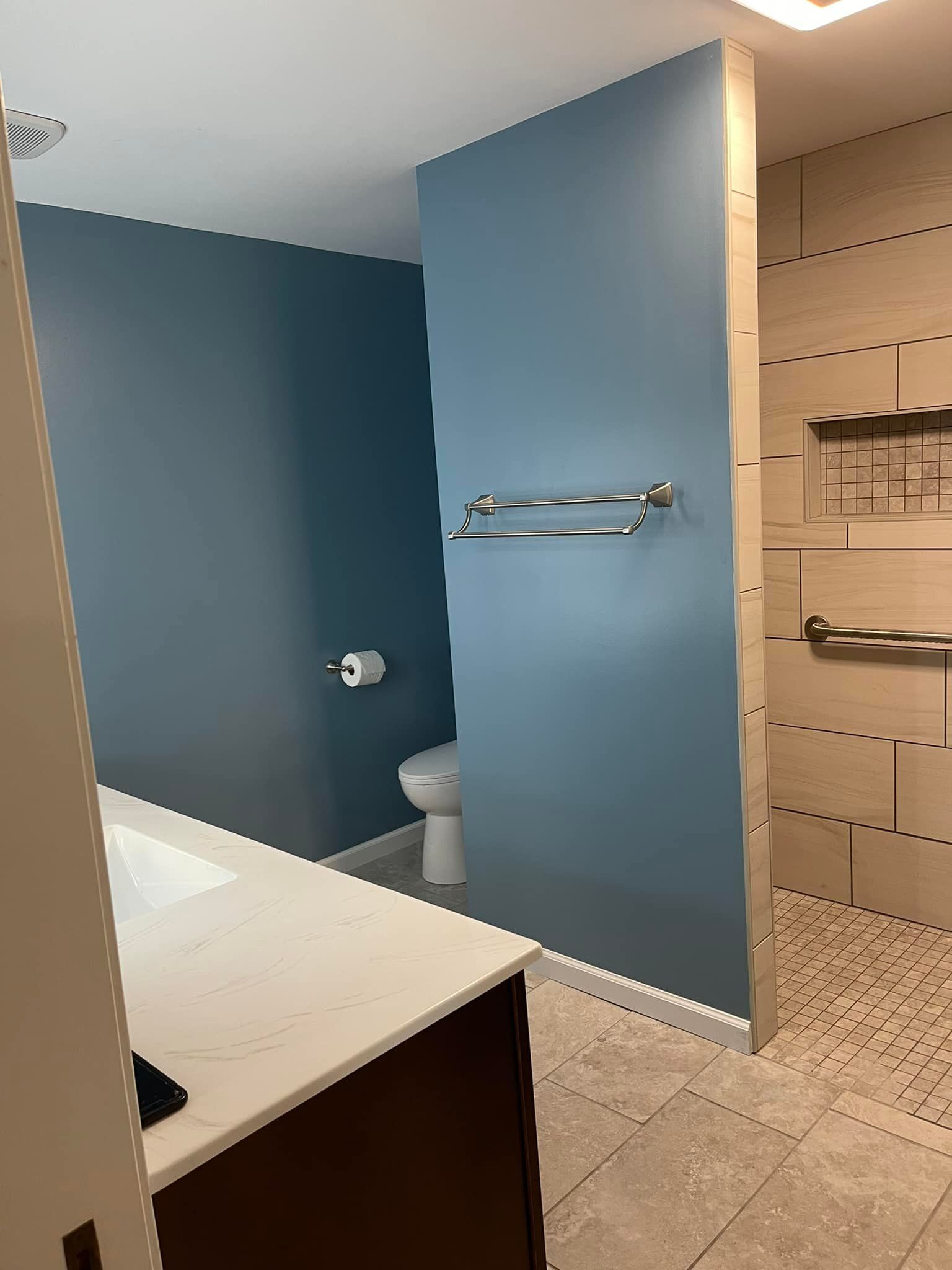A bathroom with a toilet, sink, and walk in shower.