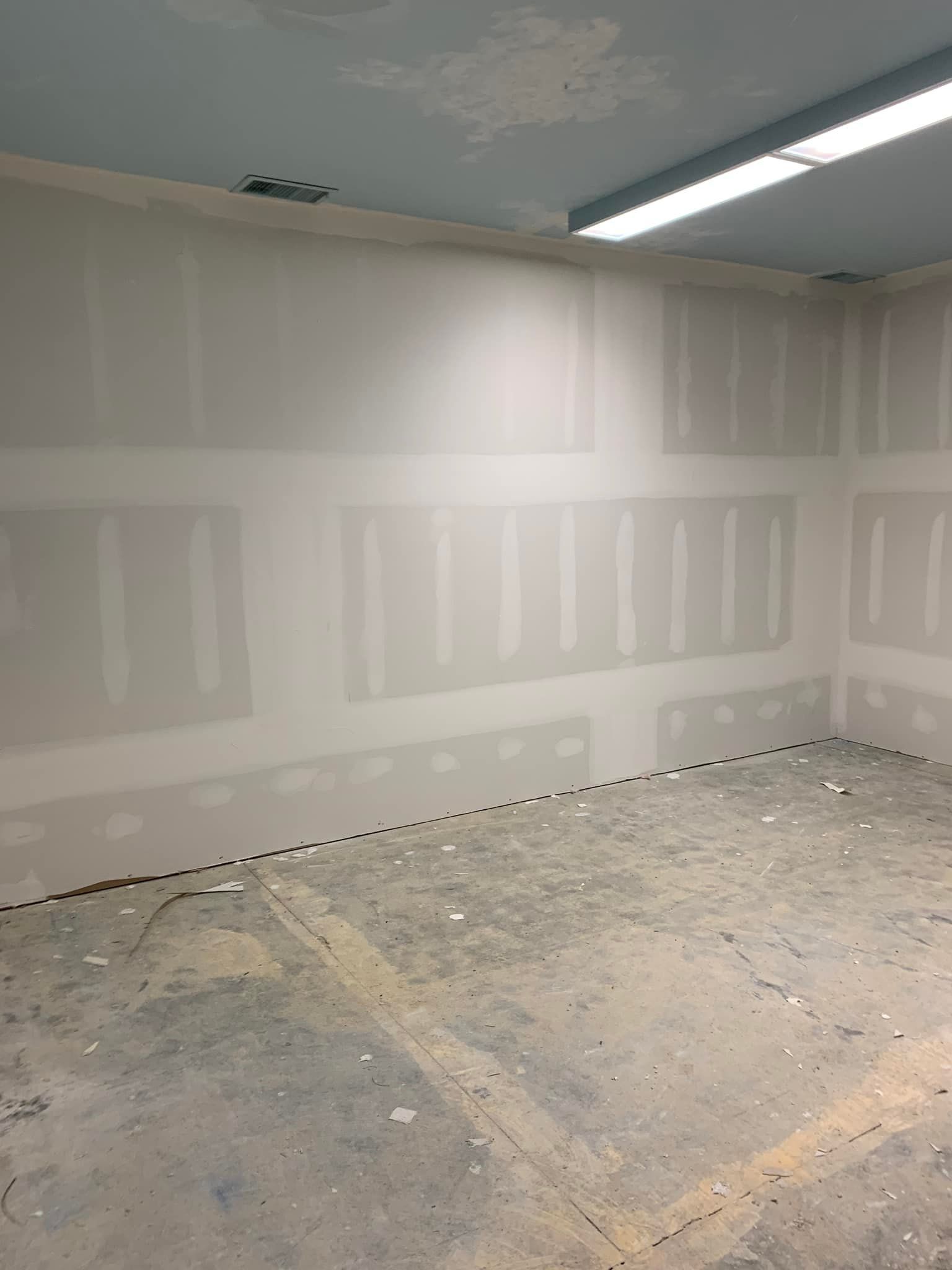 A room with drywall walls and a concrete floor.