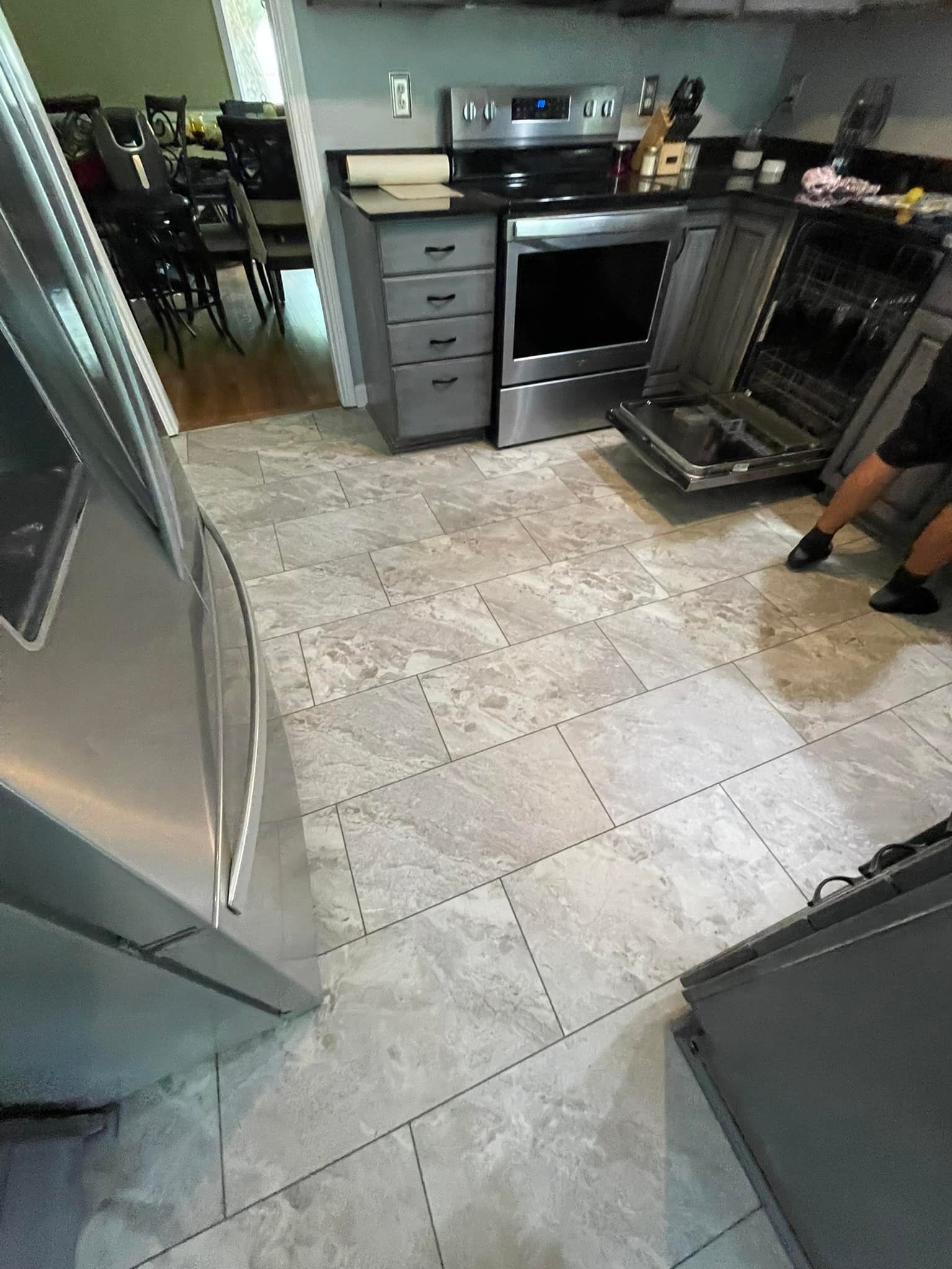 A kitchen with stainless steel appliances and a person standing in the doorway.