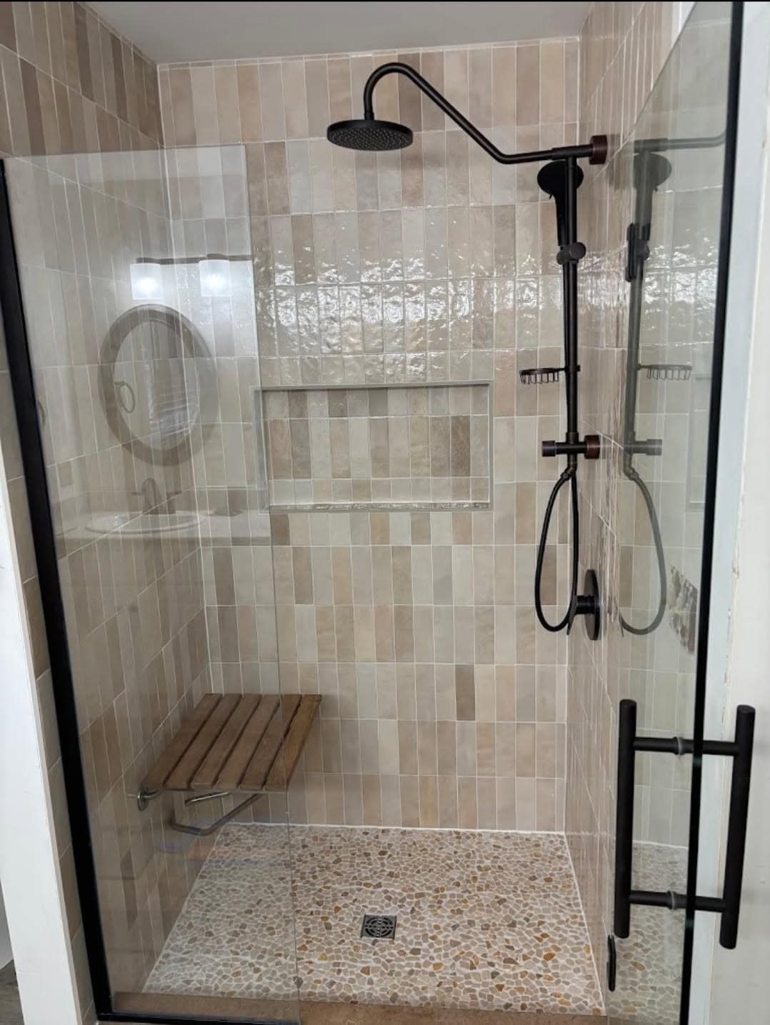 A bathroom with a walk in shower with a glass door.