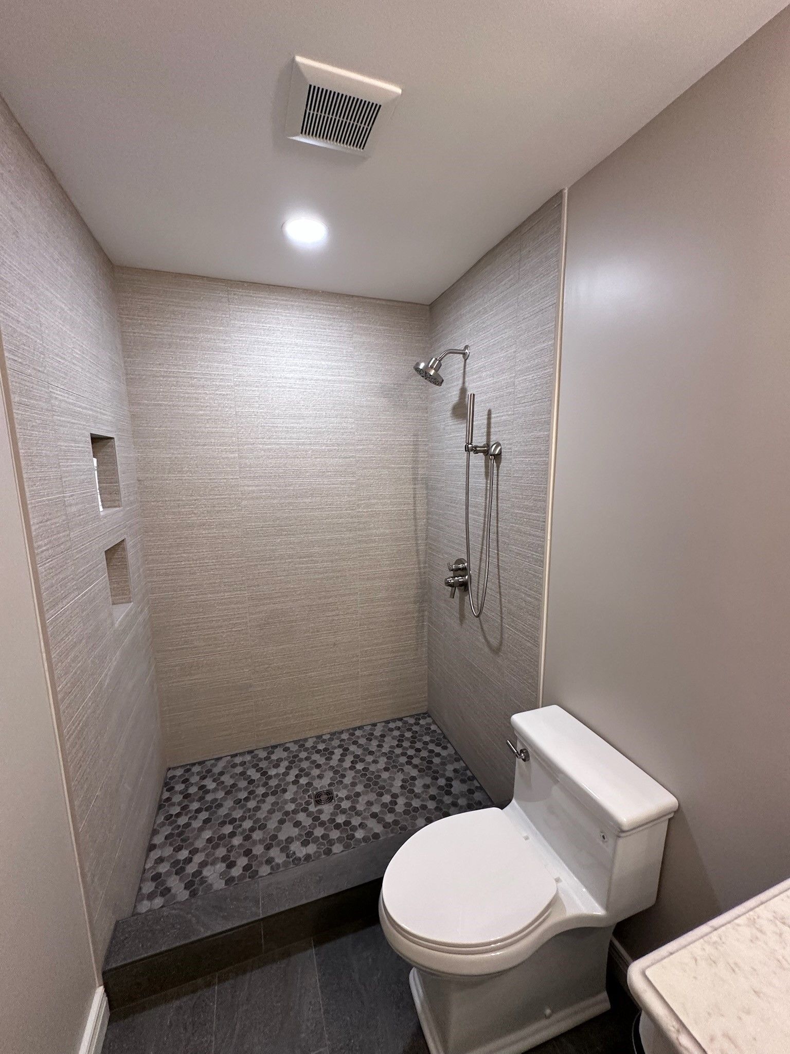 A toilet is sitting on a tiled floor in a bathroom next to a trash can.