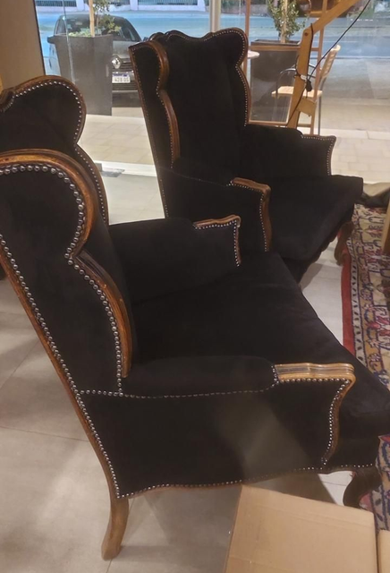 Dos sillones de terciopelo negro con detalles de madera y tachuelas; configuración interior.