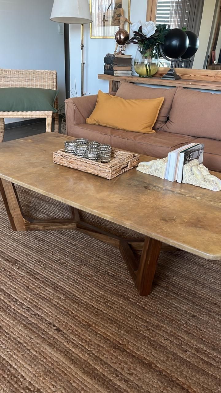 Mesa de centro de madera en una sala de estar con sofá, alfombra y decoración.