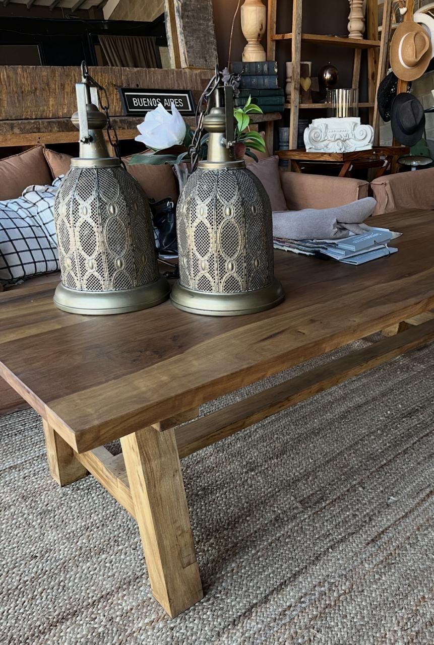 Dos faroles decorativos de metal sobre una mesa de madera, alfombra en primer plano y fondo de muebles.