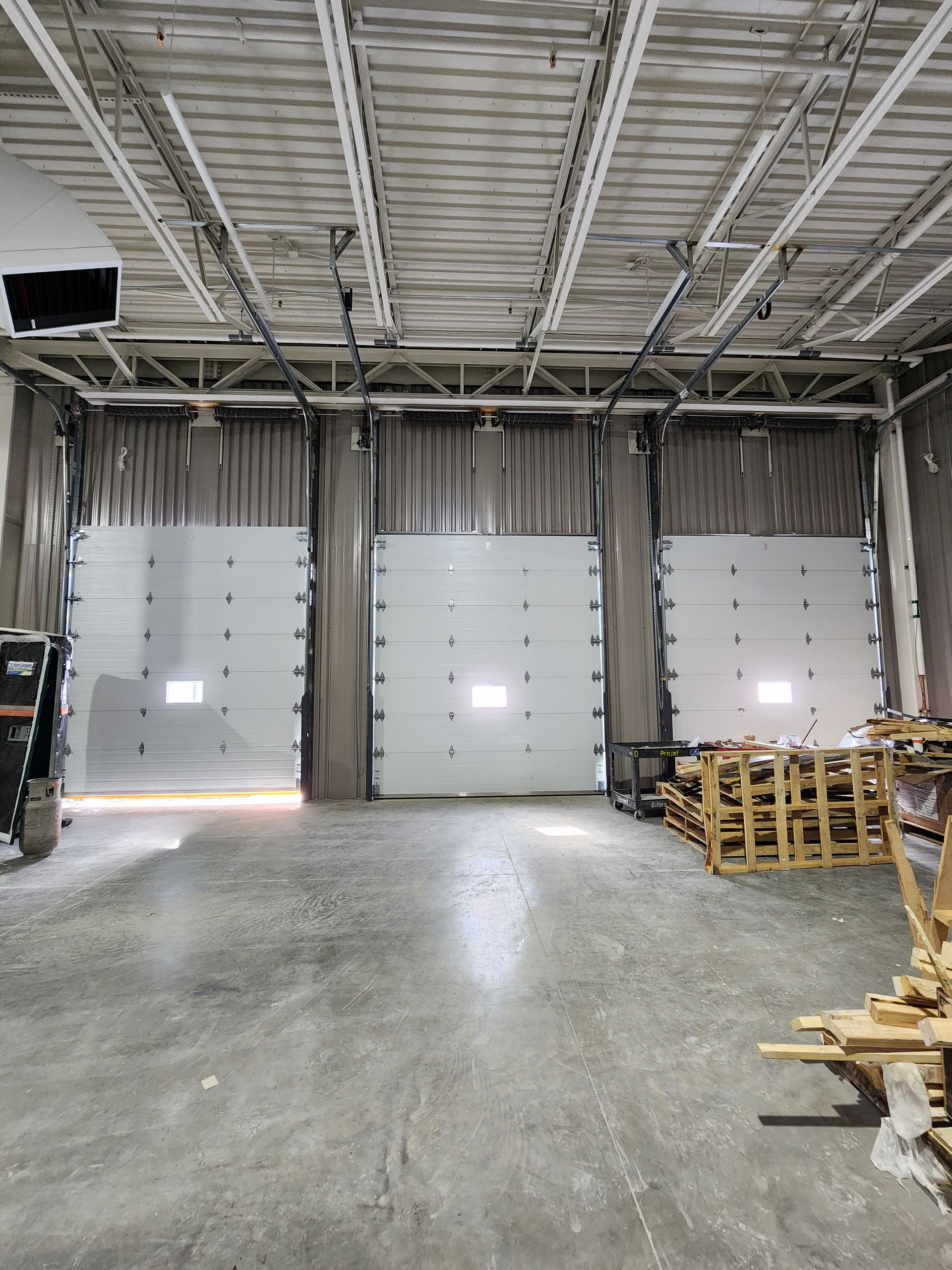 Porte de garage noire sur une façade en bois avec des finitions foncées.